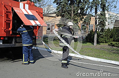 Fireman preparing firefighting equipment near firetruck before firefighting Editorial Stock Photo