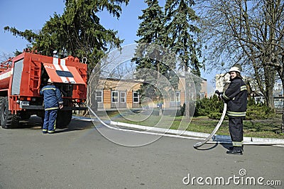 Fireman preparing firefighting equipment near firetruck before firefighting. Kyivska oblast, Ukraine Editorial Stock Photo