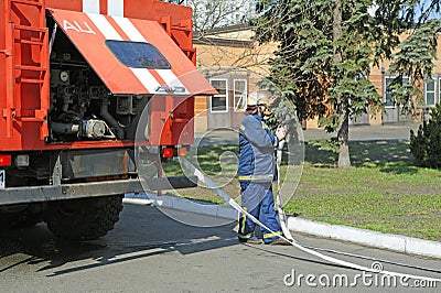 Fireman preparing firefighting equipment near firetruck before firefighting. Kyivska oblast, Ukraine Editorial Stock Photo