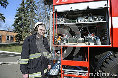 Fireman preparing firefighting equipment near firetruck before firefighting. Kyivska oblast, Ukraine Editorial Stock Photo