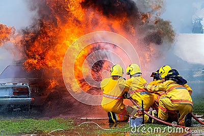 Fireman using water and extinguisher car is on fire,Firefighter using extinguisher and water from hose for fire fighting,burning c Editorial Stock Photo