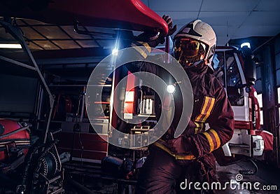 A fireman wearing a protective uniform with flashlight included working in a fire station garage Stock Photo