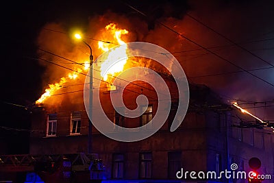 Firemen direct water stream on burning house.building in full flaming inferno, and a firefighter fighting to get control of the fl Stock Photo