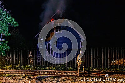 Firemen extinguish fire in rural house at night Stock Photo