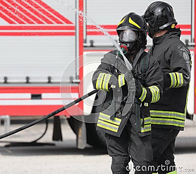 firemen with hose hydrant in action and fire engine Stock Photo