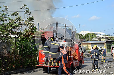 Firemen and volunteers working assembling fire hoses in fire truck in the area of a burning house Editorial Stock Photo
