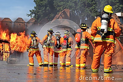 Firemen wearing fire fighter suit for safety and using water, extinguisher to fighting with fire flame in an emergency situation Editorial Stock Photo