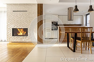 Fireplace in spacious white house interior with wooden chairs at Stock Photo