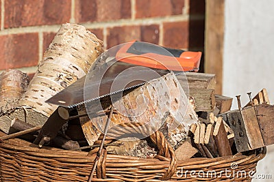 Firewood. Basket of hand sawn fire wood logs and saw Stock Photo