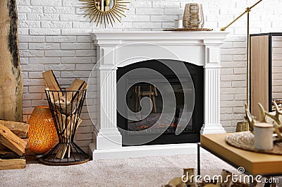 Firewood in holder near modern fireplace in living room Stock Photo