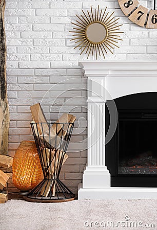 Firewood in holder near modern fireplace in living room Stock Photo