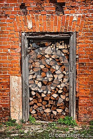 Firewood lies in the doorway, red brick wall Stock Photo
