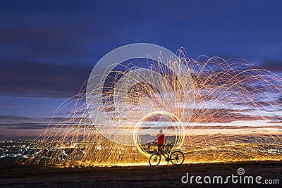 Firework showers of hot glowing sparks from spinning steel wool in night city. Stock Photo