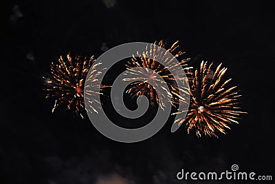 Fireworks. Firework. Heavenly background. An amazing trio of bright yellow twinkling lights in the night sky during the New Year Stock Photo