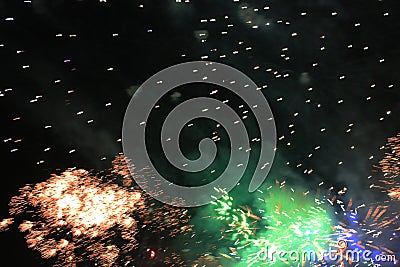 Fireworks. Firework. Heavenly background. Colorful wave of bright shimmering orange and green sparkling lights in the night sky Stock Photo