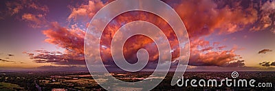 Firey storm clouds orange pink and red at sunset with distant rain storm across the landscape aerial panoramic Stock Photo