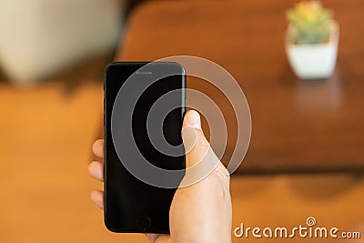 The firm grip of a male hand on a sleek mobile phone reveals a modern shopping experience. With deft fingers, he navigates through Stock Photo