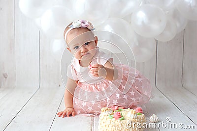 First baby birthday. Balloon garland on background. Disgruntled kid Stock Photo