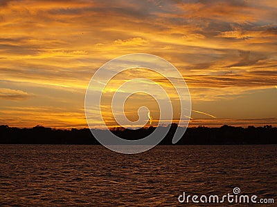 Contrails on a Colorful Sunset at a Lake Stock Photo