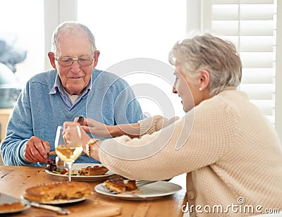 First we eat then do everything else. a senior couple eating their lunch together. Stock Photo