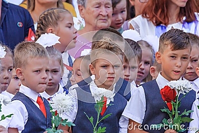 First-form schoolchildren at school on holiday of beginning of elementary education. Boys at school holiday ceremony holding Editorial Stock Photo