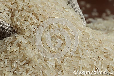 Rice grains are poured into a linen bag. Stock Photo