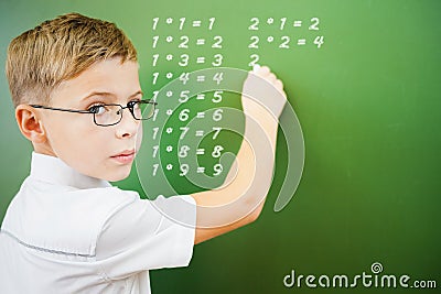 First grade schoolboy wrote multiplication table on blackboard Stock Photo