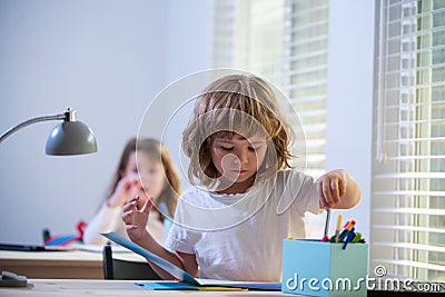 First grader. Back to school. Happy cute child is sitting at a desk indoors. Cild is learning in class. Stock Photo