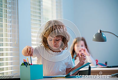 First grader. Back to school. Happy cute child is sitting at a desk indoors. Cild is learning in class. Stock Photo