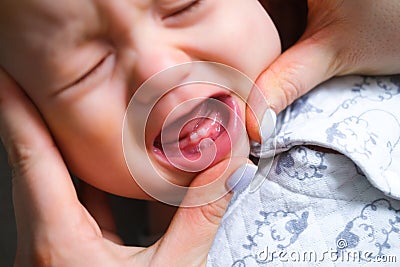 First milktooth and crying baby close up. Newborn tantrum child on mother hands. Family life, motherhood. Kids dentistry Stock Photo