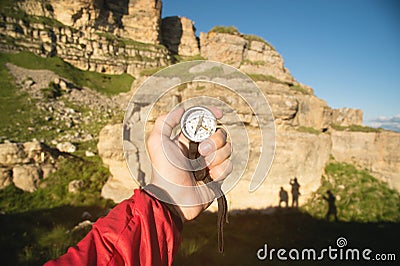 First-person view seeks direction with a compass in hand in the summer mountains. Search by destination. Three shadows Stock Photo