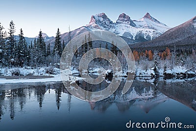 First snow Almost near perfect reflection of the Three Sisters Peaks in the Bow River. Canmore in Banff National Park Canada Stock Photo