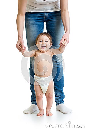 First steps of baby with mothers hands support Stock Photo