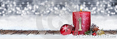 First sunday of advent red candle with golden metal number one on wooden planks in snow front of panorama bokeh background Stock Photo