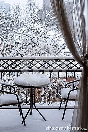 The first white fluffy snow on the table and chairs on the wrought-iron balcony. Fabulous winter Stock Photo