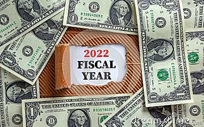 2022 fiscal new year symbol. Words `2022 fiscal year` appearing behind torn brown paper. Beautiful background from dollar bills. Stock Photo
