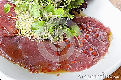 Fish Carpaccio with olives ana salad. Served on a white plate. Stock Photo