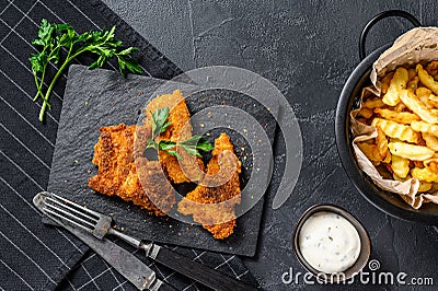 Fish and chips, French fries and cod fillet fried in breadcrumbs. Black background. Top view Stock Photo