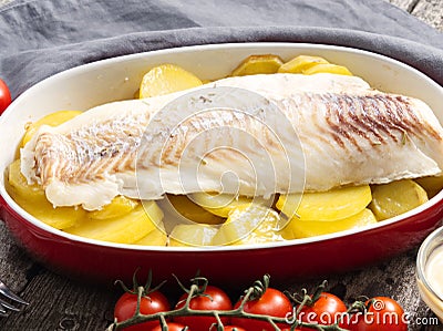 Fish cod baked in the oven with potatoes, diet healthy food. Dark old wooden rustic gray background, side view Stock Photo