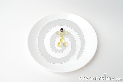 Fish oil and astaxanthin capsules on a plate in a human shape Stock Photo