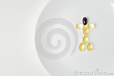 Fish oil and astaxanthin capsules on a plate in a human shape Stock Photo