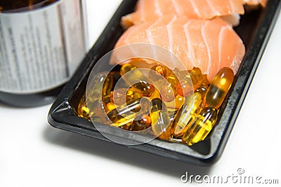 Fish oil pills served with salmon sushi on black pack with brown Stock Photo