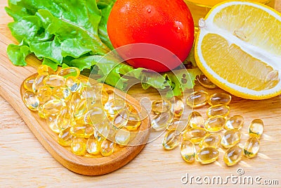 Fish oil, soft capsule, omega 3, supplement food vitamin D capsules with vegetables and fruit greens tomato lemon on wood . still Stock Photo