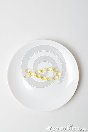 Fish oil softgels on a white plate in a shape of a fish. Meal replacement. Omega-3 polyunsaturated fatty acids on a plate. Casual Stock Photo