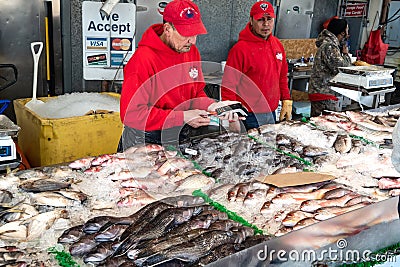 fish seller at a Washington seafood market uses a card reader to pay a customer Editorial Stock Photo