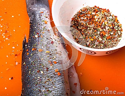 Fish and spices on a plastic cutting board. Fish in the process Stock Photo