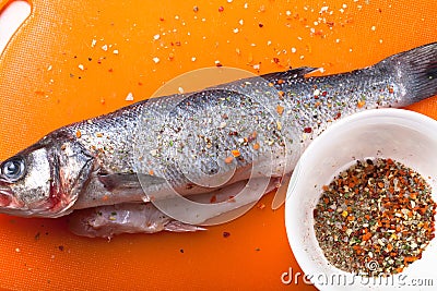 Fish and spices on a plastic cutting board. Fish in the process Stock Photo