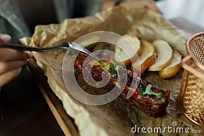 Fish tartare with slices of white baguette with salted cucumber on paper and on a wooden board in a restaurant. Light tasty snack Stock Photo