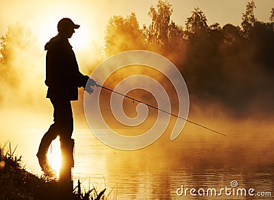 Fisher fishing on foggy sunrise Stock Photo