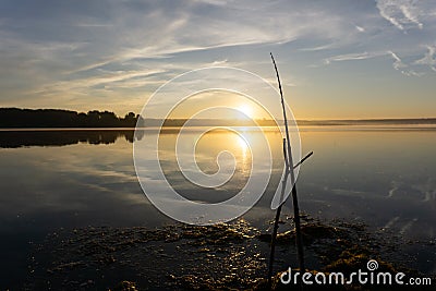 Fisher man fishing with spinning rod on a river bank at misty foggy sunrise Stock Photo